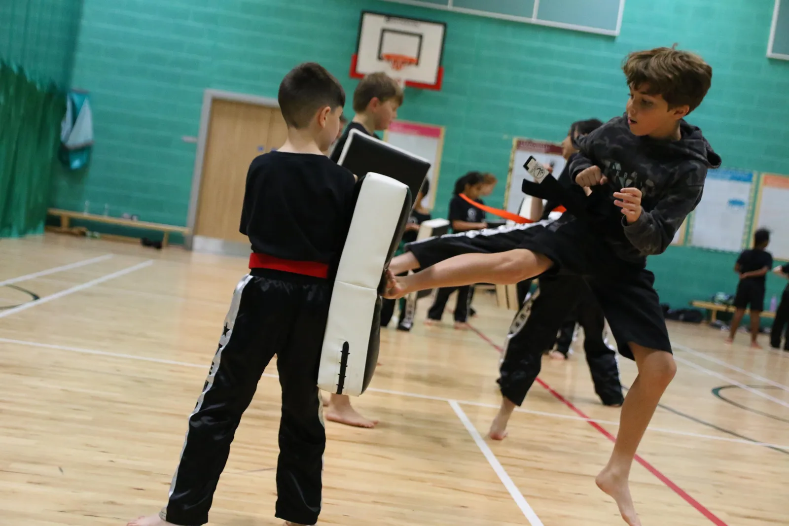 A boy leaping into a flying kick against a pad